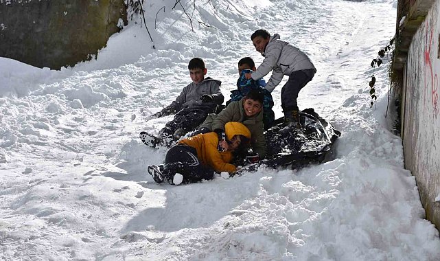 Beyaz örtüyle kaplanan mahallede poşetlerle kayarak eğlendiler