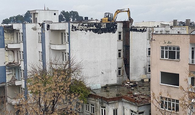 İş makinası yıkım için ağır hasarlı binanın üzerine çıkarıldı