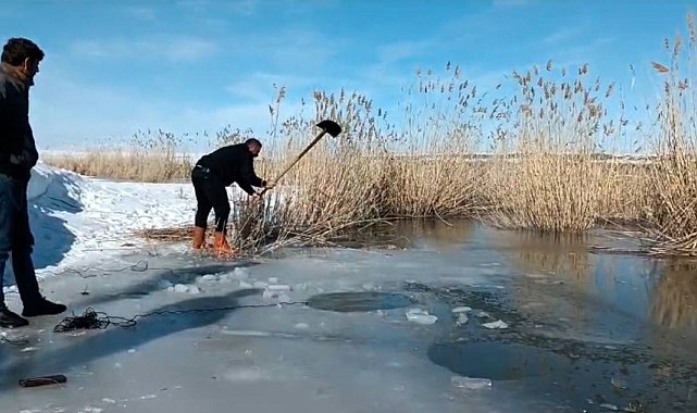 Yüzeyi donmuş nehirde buzu kırıp balık avlıyorlar