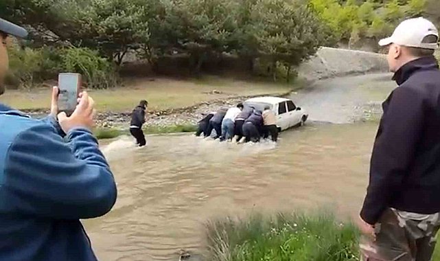 Debisi yükselen derede mahsur kalan aracı iterek kurtardılar
